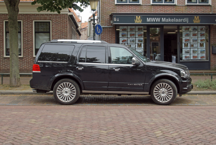 A black Lincoln Navigator parked outside of a store.