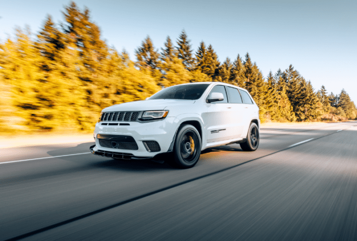 An all white Jeep Grand Cherokee driving on  the highway.
