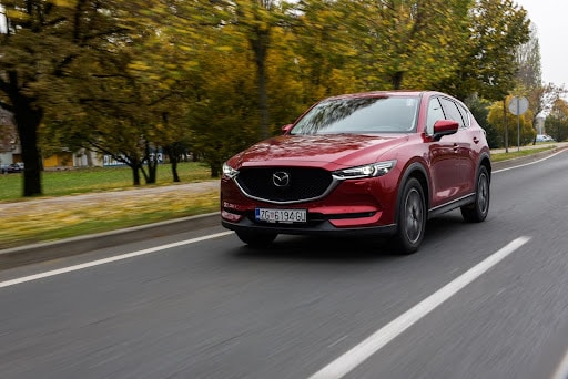 A red Mazda CX-5 Front view of the car in motion.