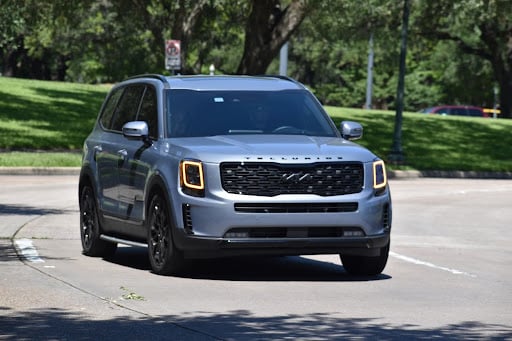 The KIA Telluride SUV cruising through a park.