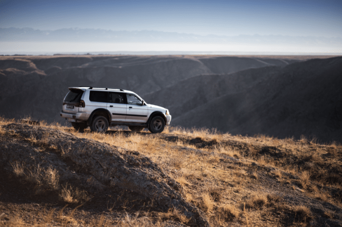 An SUV parked outside on the side of a mountain.